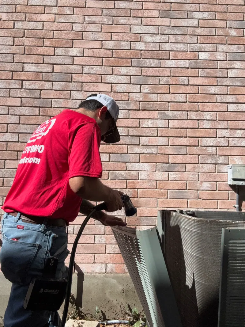 Yeti technician cleaning a condenser coil during an AC tune-up