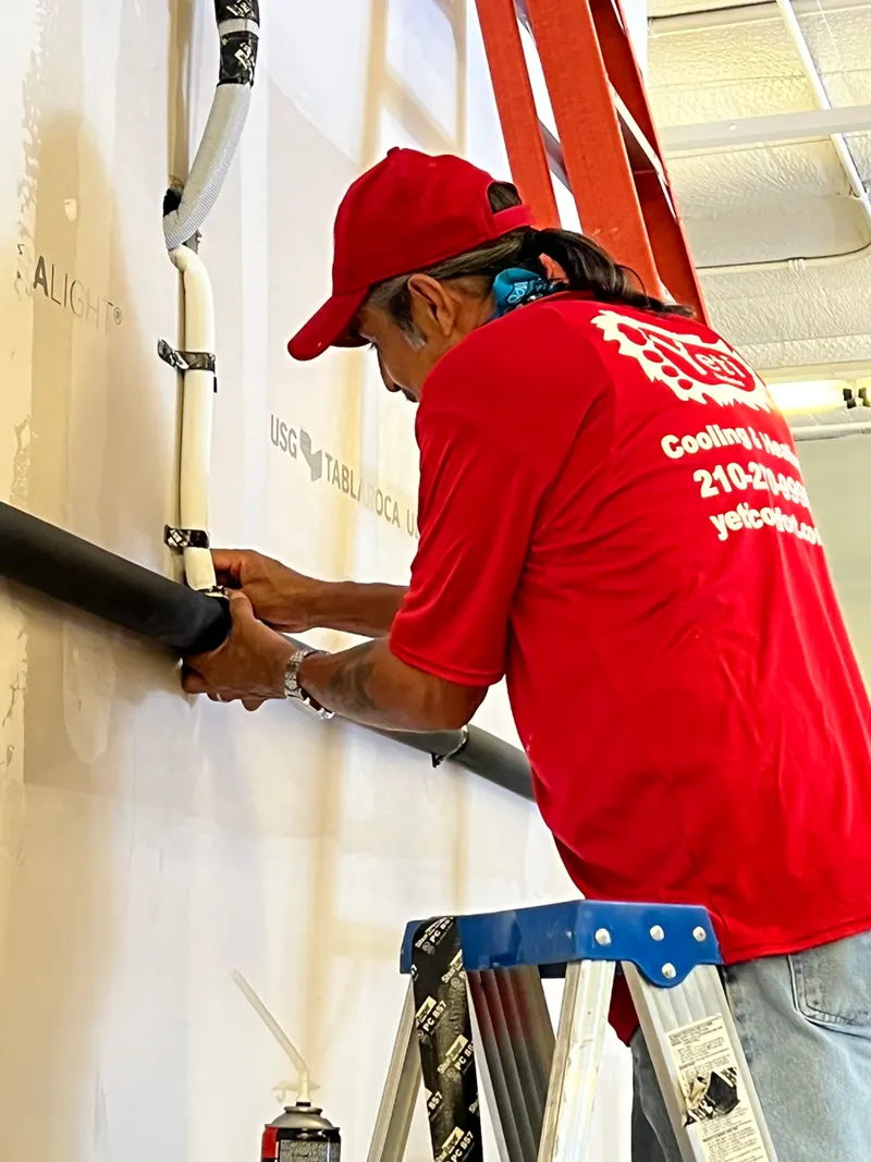 Yeti technician in a branded shirt insulating a refrigerant line set